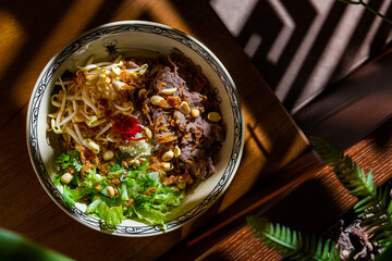 Salad with pieces of meat, peanuts, lettuce, sprouts, peppers, fried onions and parsley
