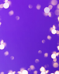 Christmas bright gold colors bokeh different sizes around the frame on vibrant purple blurred background. Holiday template and shiny greeting concept with copy space