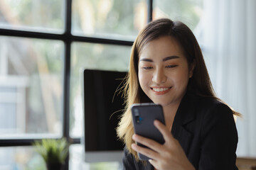 Fototapeta premium Businesswoman looking at financial information from a mobile phone, she is checking company financial documents, she is a female executive of a startup company. Concept of financial management.