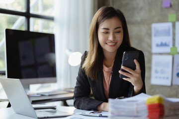 Businesswoman looking at financial information from a mobile phone, she is checking company financial documents, she is a female executive of a startup company. Concept of financial management.