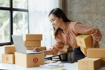 A beautiful Asian business owner opens an online store, she is checking orders from customers,...