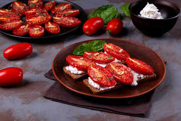 Bruschetta with roasted tomatoes on cream cheese and rye crisp bread served on clay plate