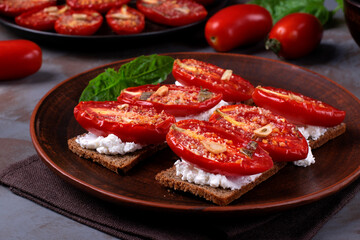 Bruschetta with roasted tomatoes on cream cheese and rye crisp bread served on clay plate