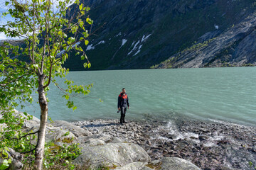 Tourist at Nigardsbreen glacier lake with camera in hand in Norway