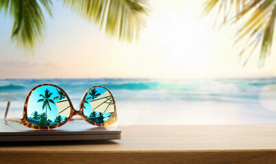 Art Computer and sunglasses on a wooden table. against the backdrop of sunset, the sun over a warm...