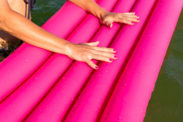 Sexy woman holding pink inflatable mattress in water