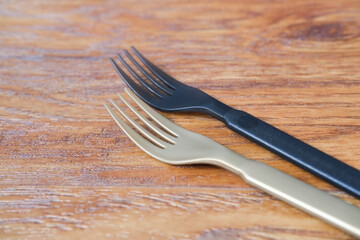 golden and black plastic fork on a wooden surface