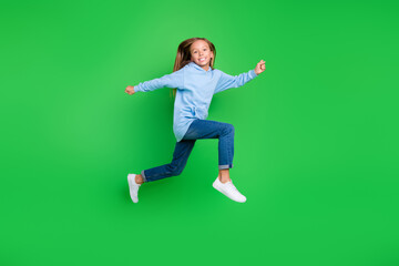 Fototapeta na wymiar Full body photo of cute little schoolkid girl smile running through air dressed trendy blue sportswear isolated on green color background