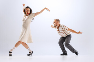 Rhythm and expression. Energetic dance couple in retro style outfits dancing lindy hop, jive isolated on white background. 50s, 60s ,70s american fashion style.