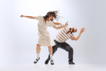 Rhythm and expression. Energetic dance couple in retro style outfits dancing lindy hop, jive isolated on white background. 50s, 60s ,70s american fashion style.