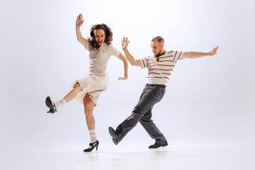 Fototapeta na wymiar Rhythm and expression. Energetic dance couple in retro style outfits dancing lindy hop, jive isolated on white background. 50s, 60s ,70s american fashion style.