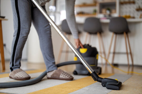 Woman using vacuum cleaner at home, close up