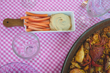 Table with paella and hummus with carrot sticks