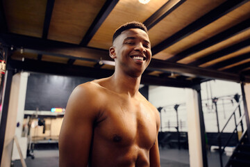 Fototapeta na wymiar Happy African American male looking to the camera. Topless mixed race male exercising indoors in the gym with skipping rope. High quality photo
