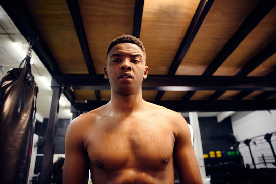 African American male looking serious to the camera. Topless mixed race male exercising indoors in the gym with skipping rope. High quality photo