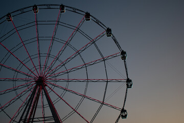 The Ferris wheel without people in the clear blue sky glowing with different colors. Ferris wheel...