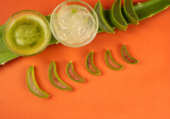 Slices of Aloe Vera leaf and Aloe Vera gel in a bowl on orange background. Aloe Vera is a very useful herbal medicine for skin care and hair care.