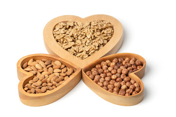 Variety of nuts in wooden cups in the shape of a heart isolated on a white background.