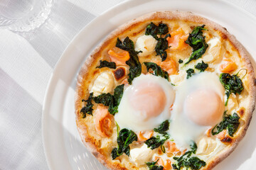 Pizza with fried egg, shrimps, cheese and spinach