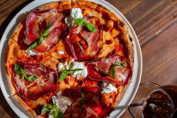 Pizza with prosciutto, cheese, sauce, basil and ketchup