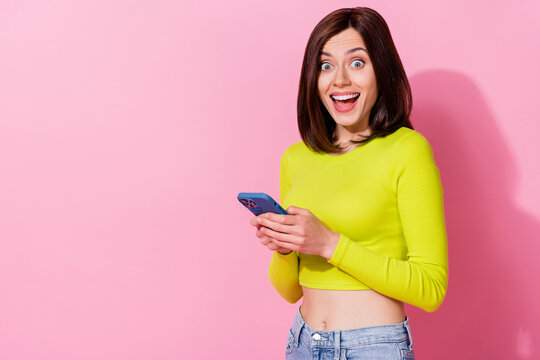 Photo of impressed shiny lady wear yellow top communicating modern gadget empty space isolated pink color background