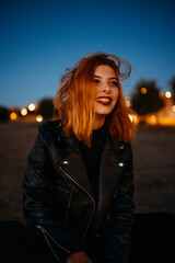 Portrait of a beautiful young woman with red air smiling at the blue hour / sunset