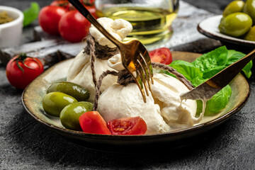 Antipasto burrata cheese salad served with cherry tomatoes, fresh basil leaves, prosciutto ham and...