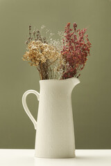 Ceramic jug with bunch of various dried flowers and plants