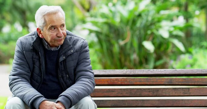 Lonely, senior and depressed caucasian man sitting in the park looking bored from being retired. Sad, annoyed and.dissatisfied elderly person sitting on a bench. Upset and frustrated pensioner