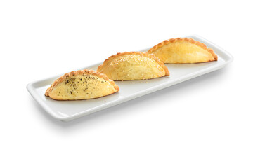 Three freshly baked empanadas on a rectangular ceramic plate, isolated on white