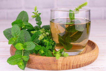 Mint tea. Medicinal mint tea in a glass and fresh mint on a wooden tray.
