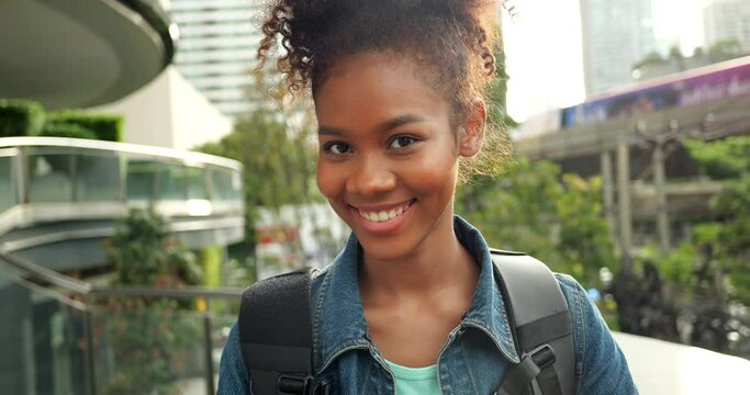 african american portrait Afro hair, Portrait of black female travel city in metropolis. Wear headphones backpack travel abroad in city. Smiling portrait woman smile happy gesture.