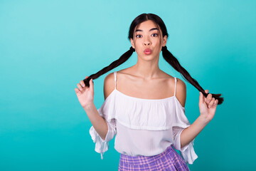 Portrait of pretty adorable thai girl hands hold tails kiss lips isolated on bright teal color background