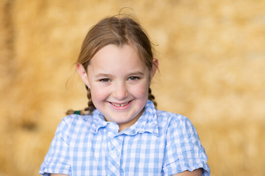 young girl smiling bashfully looking at camera with blurry background