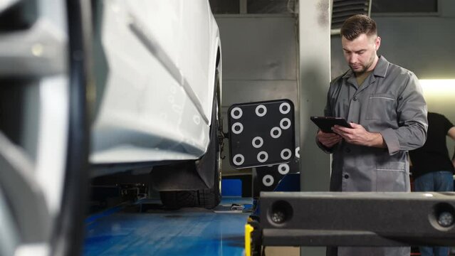 A Car Service Employee Installs A Wheel Adapter With A Target On The Wheel To Perform A Wheel Alignment. Diagnostics And Balancing Of Wheels Of A Lifting Trolley At A Modern Service Station.