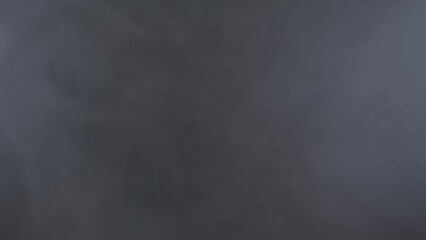 A dark room filled with smoke, desaturated grey steam cloud slowly moving towards the center. Useful background or overlay.
