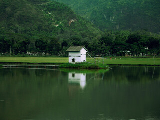 Fototapeta na wymiar Small white house on the lake. House on the lake. Landscape background.