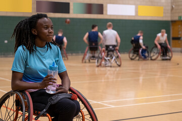 Teenage girl in wheelchair having water break during basketball game