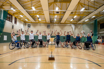 Team portrait of basketball players in wheelchairs with trophy