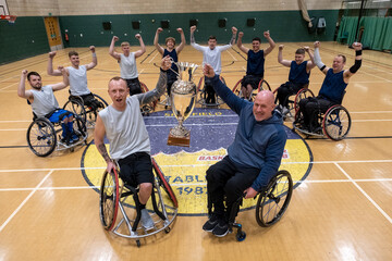 Team portrait of basketball players in wheelchairs with trophy