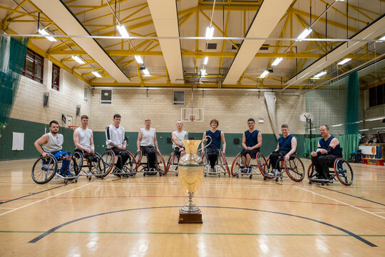 Team portrait of basketball players in wheelchairs with trophy