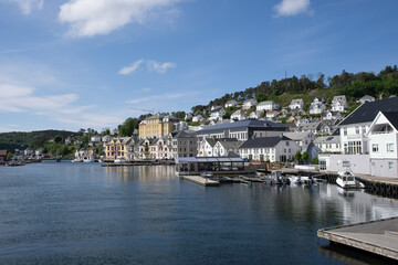 Fototapeta na wymiar Farsund, Norway - May 30, 2022: Panoramic view of the city and many islands from a hill in a sunny spring day. A spectacular view to Lyngdalsfjorden and town suburbs. Trees, sunny day. Selective focus