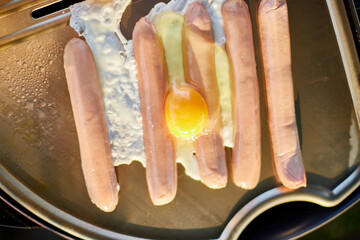 Fototapeta Prepare breakfast roasting bruschetta, sausages and eggs on the barbecue gas grill obraz