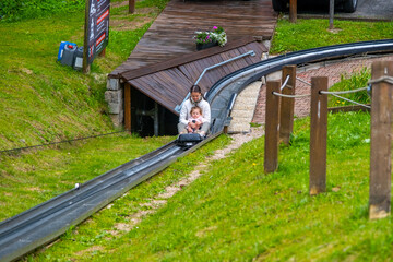 Mom and daughter are skating down on summer bobsled track near Spindleruv Mlyn town in Czech...