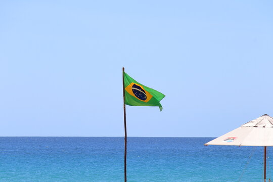 Waving Brazilian Flag against Conceicao beach background at Fernando de Noronha, Brazil, in a sunny august morning