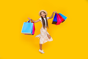 teen girl smile with shopping bags on yellow background. full length