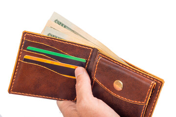 A man is holding an open brown wallet with money and credit cards