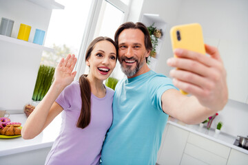Fototapeta Photo of two positive partners take selfie recording video arm palm waving kitchen house indoors obraz