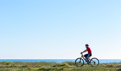 Teenage boy riding a bike on a seaside bike path