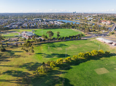 Aerial view of urban sports fields separated by a road and rows of trees